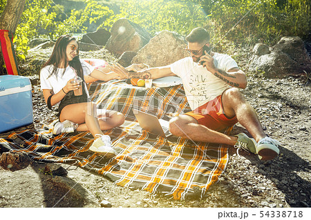 Young couple having picnic at riverside in sunny day Young couple having picnic at riverside in sunny day 54338718