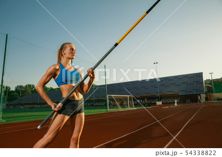 Female high jumper training at the stadium in sunny day Female high jumper training at the stadium in sunny day 54338822