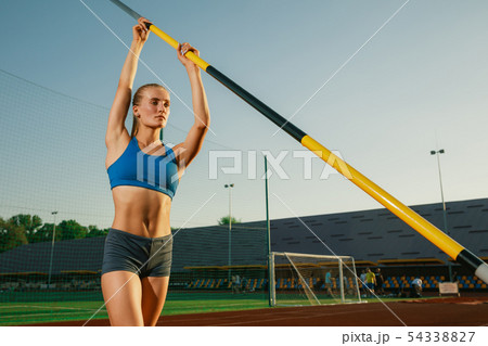Female high jumper training at the stadium in sunny day Female high jumper training at the stadium in sunny day 54338827