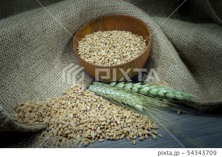 Wheat seeds spilling from a bowl with ears 54343709