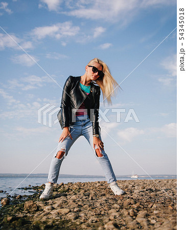 Girl in ripped jeans having fun on the shore of the blue sea Girl in ripped jeans having fun on the shore of the blue sea 54345018