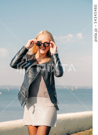 Beautiful blonde in black sunglasses posing on the shore of the blue sea 54345460