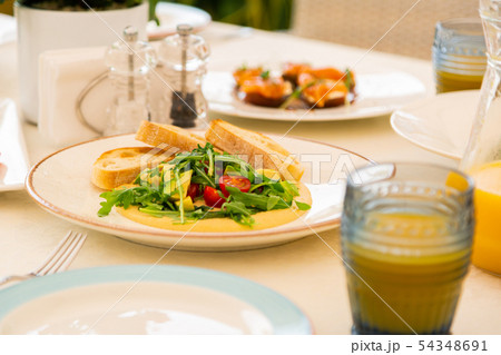 Bruschetta lying on plate near arugula and avocado salad Bruschetta lying on plate near arugula and avocado salad 54348691