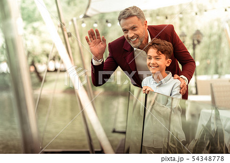 Father and son waving seeing mother coming to restaurant Father and son waving seeing mother coming to restaurant 54348778