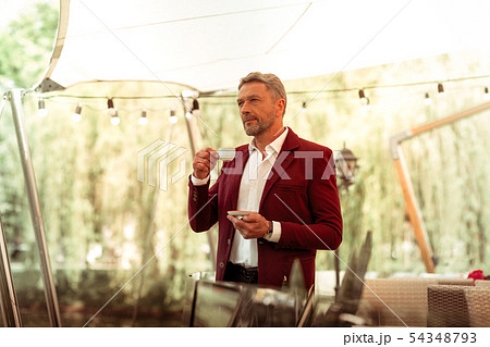 Businessman standing on summer terrace and drinking coffee 54348793