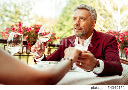 Bearded grey-haired businessman having romantic dinner with wife Bearded grey-haired businessman having romantic dinner with wife 54349131