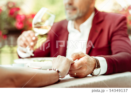 Bearded husband drinking wine while holding hand of his wife 54349137