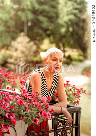 Appealing mature stylish woman feeling thoughtful standing on balcony Appealing mature stylish woman feeling thoughtful standing on balcony 54349402