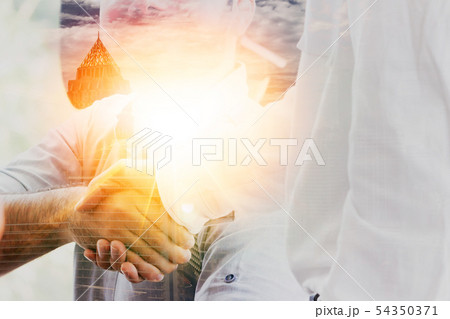 Double Exposure of business men shaking hands with cityscape and sun in background Double Exposure of business men shaking hands with cityscape and sun in background 54350371