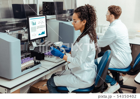 Serious dark haired woman holding a special scanner 54350402