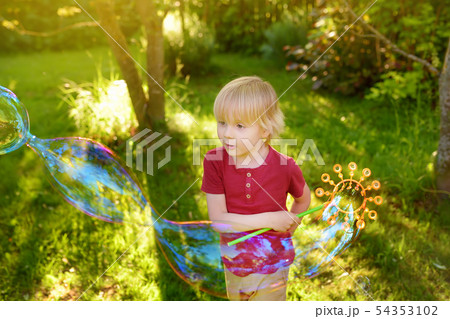 Cute little boy is playing with big bubbles 54353102