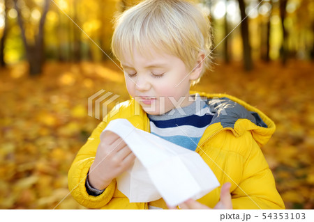 Little boy sneezing and wipes nose with napkin Little boy sneezing and wipes nose with napkin 54353103