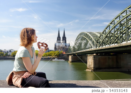 Young woman eats traditional pretzel sitting on Young woman eats traditional pretzel sitting on 54353143