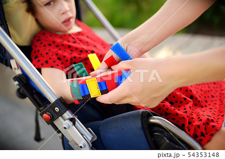 Mother puts orthosis on her daughter arms. 54353148