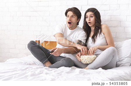 Portrait of couple watching scary movie while lying on the bed 54353805