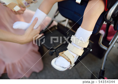 Mother puts on orthosis her daughter legs. 54354344