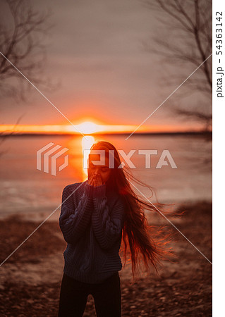Woman enjoying time relaxing by the beautiful lake at sunrise. 54363142