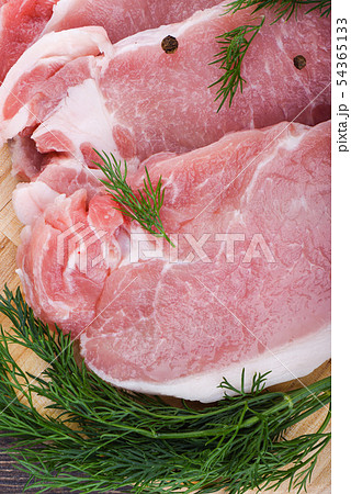 Pork steaks on a wooden cutting board with dill 54365133
