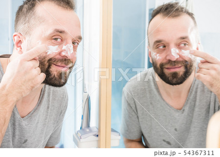 Man applying moisturizer cream in bathroom 54367311