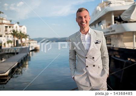 Handsome businessman is wearing white fashion costume stands on the background of the bay with 54368485