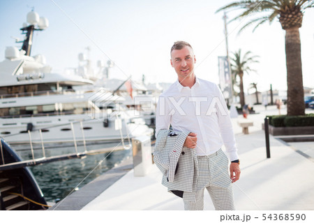 Stylish businessman is wearing white fashion costume stands on the background of the bay with luxury 54368590