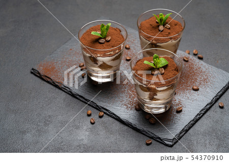 Classic tiramisu dessert in a glass on stone serving board on dark concrete background 54370910
