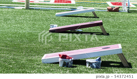 Three corn hole games set up on turf field 54372451