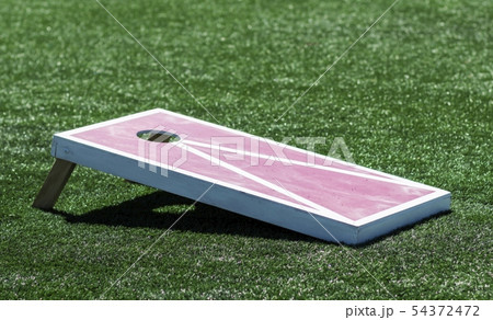 Side view of homemade cornhole game on turf field 54372472