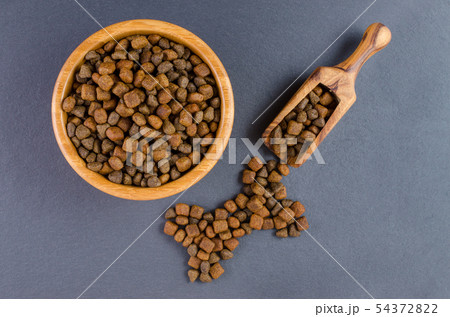dog food in a bowl and snack like bone on black background, top view dog food in a bowl and snack like bone on black background, top view 54372822