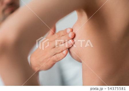 Close up of plastic surgeon touching nipples before augmentation 54375581