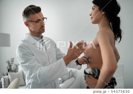 Plastic surgeon wearing glasses making measurements of breast 54375630