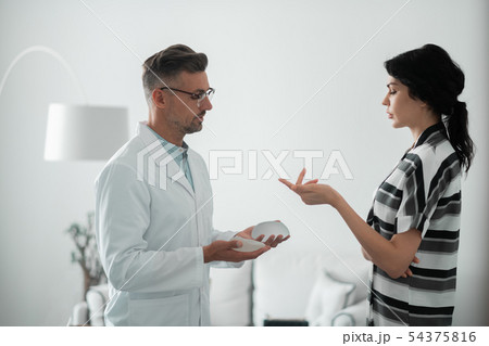 Dark-haired woman asking questions about implants for breast 54375816