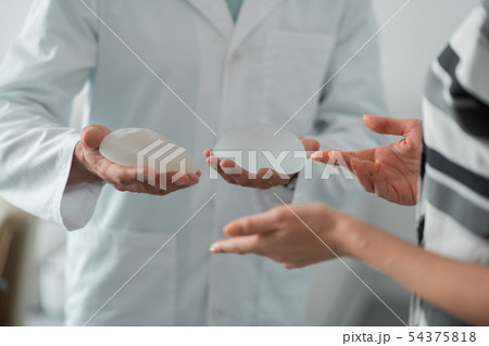 Plastic surgeon wearing white lab coat holding implants for breast Plastic surgeon wearing white lab coat holding implants for breast 54375818