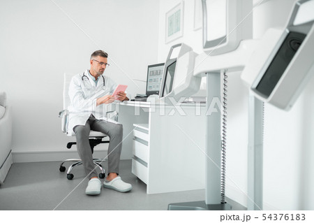 Professional plastic surgeon wearing uniform working on tablet 54376183