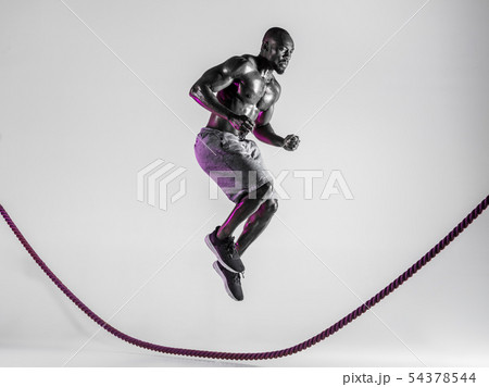 Young african-american bodybuilder training over grey background 54378544