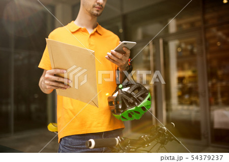 Young man as a courier delivering package using gadgets 54379237