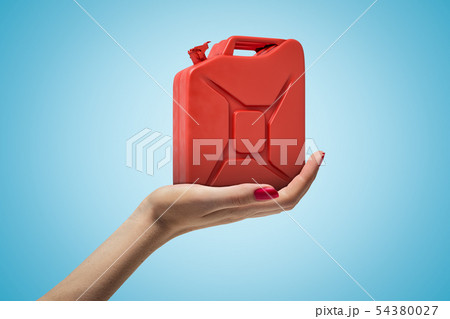 Side closeup of woman's hand facing up and holding red metal jerrican on light blue gradient 54380027