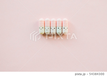 Row of Funny pink capsule on a pastel paper pink Row of Funny pink capsule on a pastel paper pink 54384300