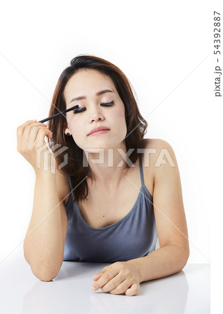 studio shot young woman applying make-up 54392887