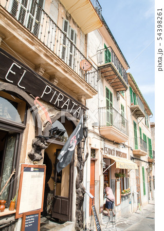 マヨルカ島の街並み　レストランと遮光扉の付いた窓のある薄あずき色の壁と石壁の家々 54398261