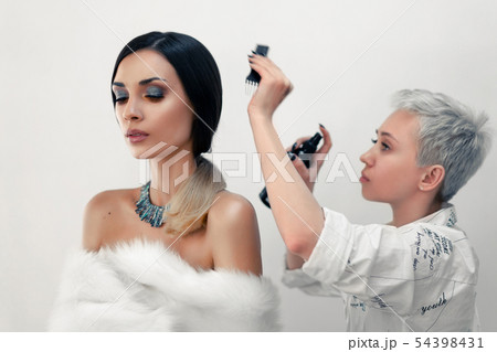 Hair stylist straightens hair beautiful model on 54398431