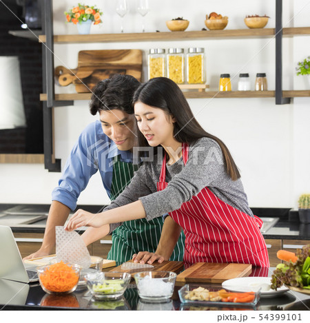 Asian couple in apron make a salad together.. 54399101