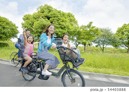 新緑の公園で自転車に乗る4人家族の写真素材