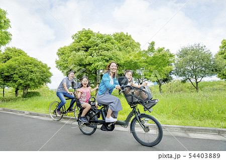 新緑の公園で自転車に乗る4人家族の写真素材