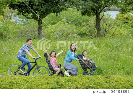 新緑の公園で自転車に乗る4人家族の写真素材