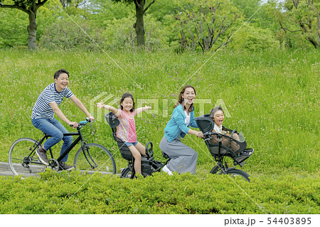 新緑の公園で自転車に乗る4人家族の写真素材