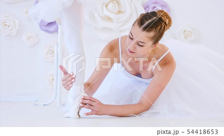 Ballet teacher is helping little girl to stretch feet lifting standing on tiptoe Ballet teacher is helping little girl to stretch feet lifting standing on tiptoe 54418653