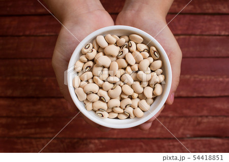Hands holding black eyed beans in white bowl. Hands holding black eyed beans in white bowl. 54418851