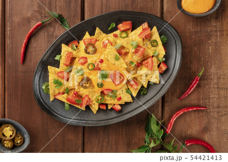 Nachos, Mexican tortilla chips, shot from above with a cheese sauce, chili and jalapeno peppers 54421413