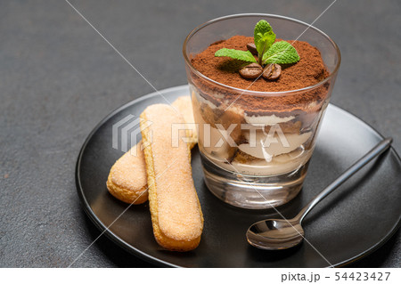 Classic tiramisu dessert in a glass and savoiardi cookies on dark concrete background 54423427